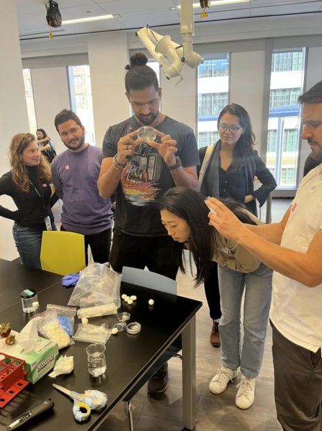 Three female and 3 male attendees examining silk film and cocoons