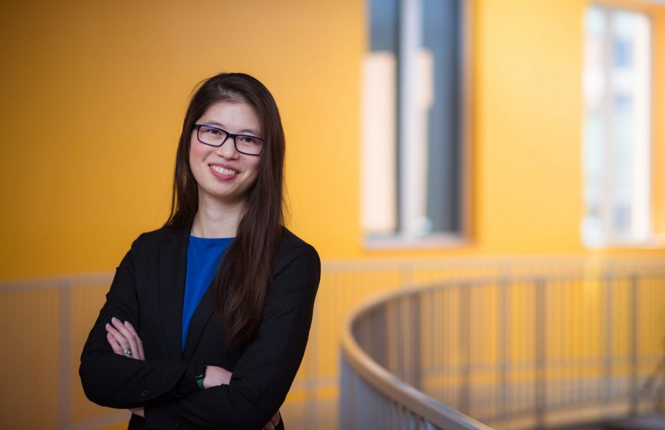 Headshot of Cathy Wu standing in front of a yellow wall.