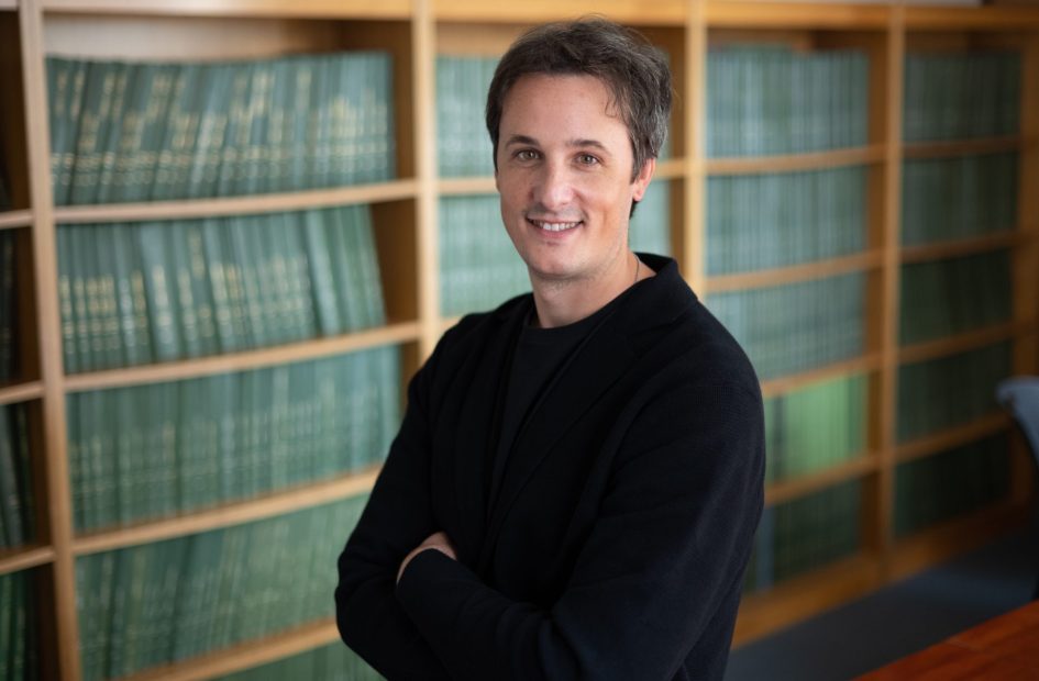 Headshot of Cesar Terrer standing in front of a bookshelf.